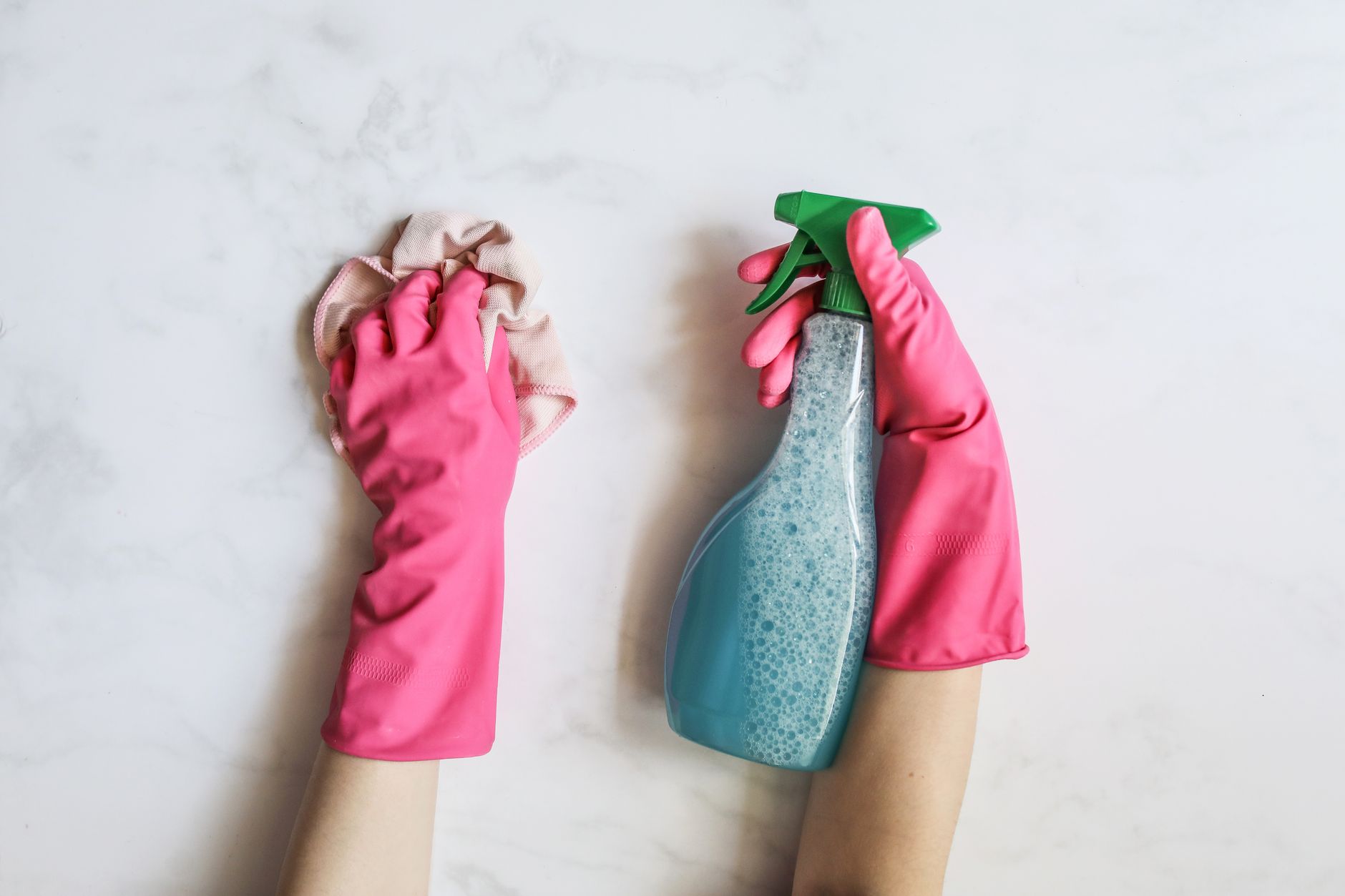 Bucket of cleaning supplies with spray bottles, gloves and cloths